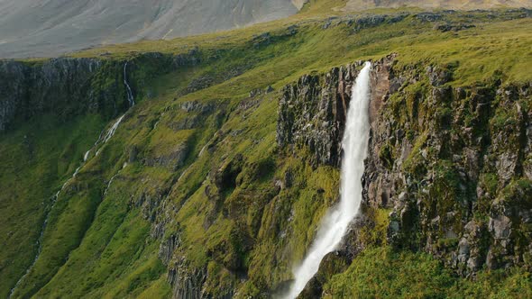 Aerial Drone Footage of Bjarnarfoss Waterfall Green Cliff Edge Located in Western Iceland