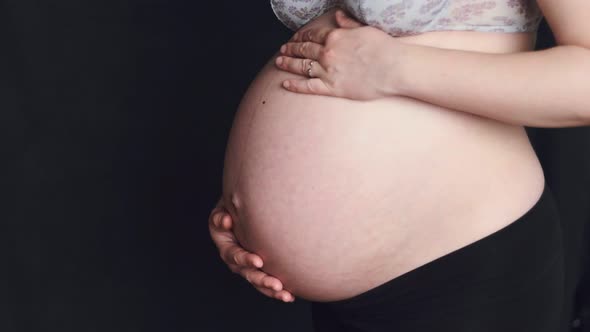 Midsection of pregnant woman dancing and holding baby belly