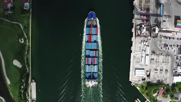 Cargo Ship Filled with Freight Moves Between the Residential Area and the Docks in Port Miami. alt