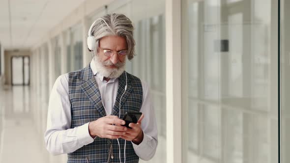 Hipster Businessman in Earphones Listening To Music with Smartphone