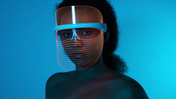 Woman wearing blue light therapy mask against blue wall