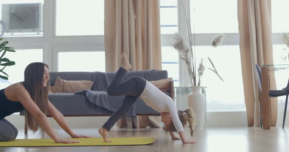 Young Beautiful Woman and Her Little Baby Girl Training Stretching Yoga at Home