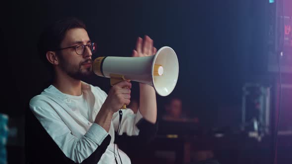 A Male Director on the Set Shouts Into Megaphone to the Actors