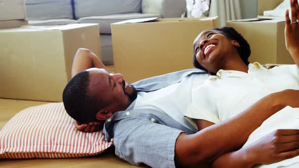 Smiling couple lying on floor and talking in living room