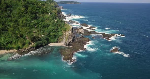 Sliding drone shot of Aerial coastline with green trees and Plantation beside blue Ocean in summer -