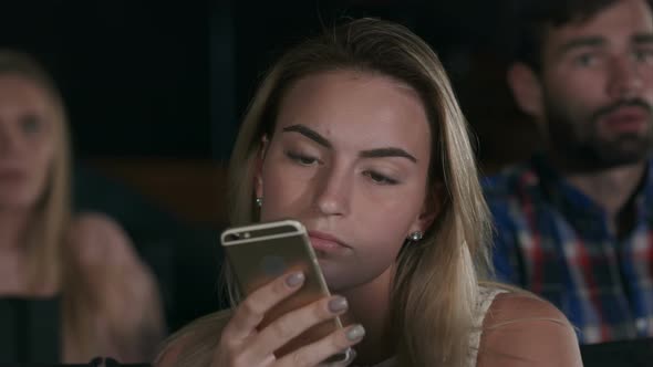 Shot of a Beautiful Young Female Texting During Movies at the Local Cinema