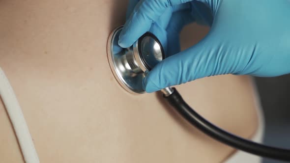 Closeup of Doctor Hand Using Stethoscope with a Female Patient Checking the Lungs and Heart Beat