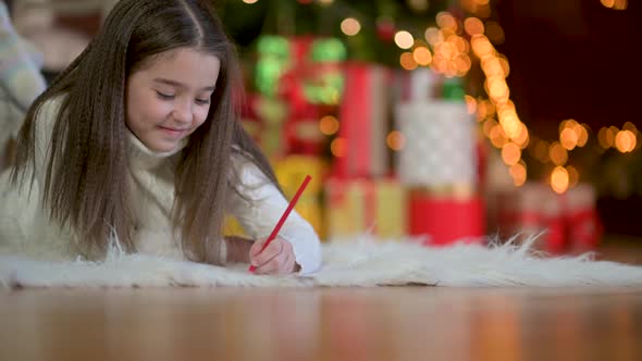 cute little girl lies on the floor and writes a letter to Santa Claus