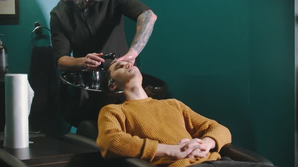 Man Barber with Tattoes Washing His Client Hair