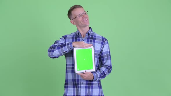 Portrait of Happy Hipster Man Thinking While Showing Digital Tablet