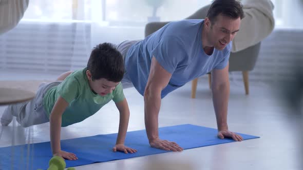 Active Man with Preteen Son Doing Pushups at Home