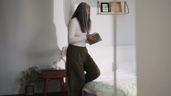 Smiling Asian woman walking to read book