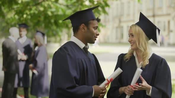 Classmates in graduation outfit talking, hugging and congratulating each other