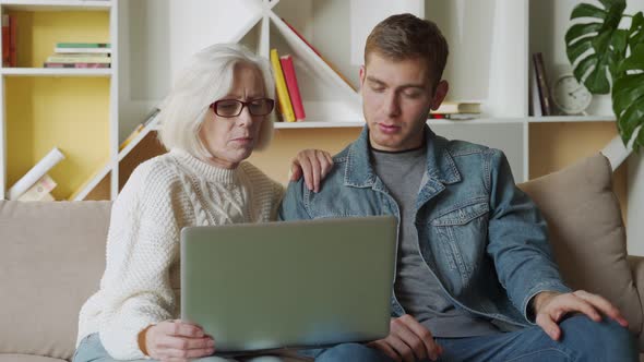 Middle Aged Man Helping His Mother Use a Laptop Computer at Home