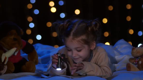 Little Girl at Night Reading a Book on the Bed, Bokeh Background