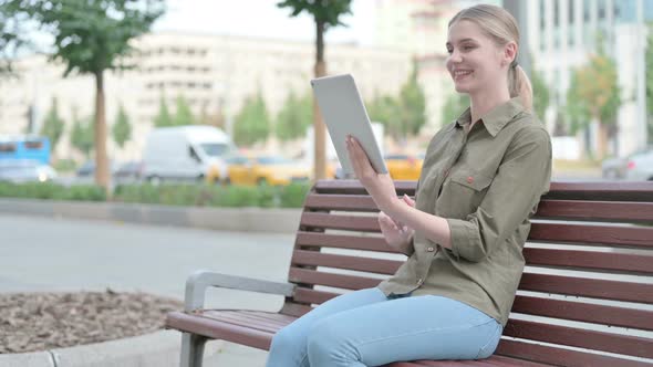 Online Video Chat on Tablet by Woman Sitting Outdoor on Bench
