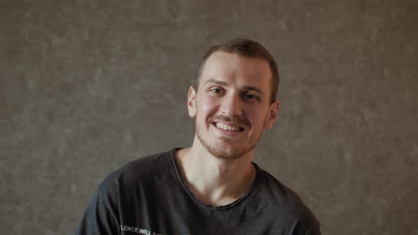 Young man laughing against gray background