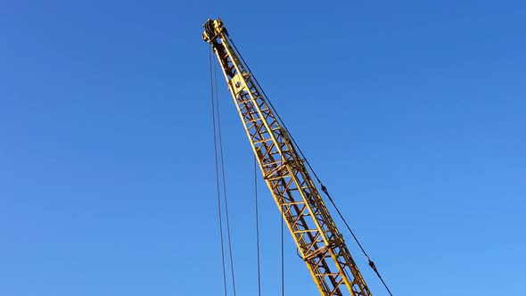 Jib Arm of Yellow Truck Crane Standing Against Blue Sky