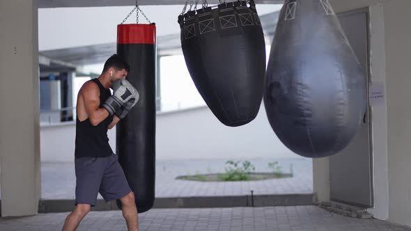 Full Length of a Boxer Traing on Boxing Bag in Parking Zone Gym