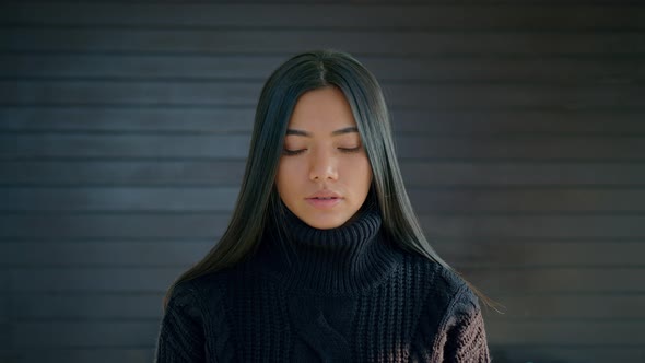 Beautiful Brunette Woman with Lovely Long Hair in a Black Sweater Looks Straight at the Camera