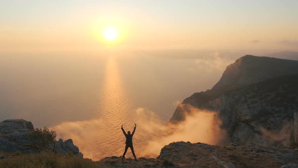 Young Girl Stands on the Edge of a High Mountain and Enjoys an Unusual Landscape at Sunset Over the