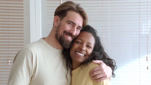 Young Multiethnic Heterosexual Couple Looking at Camera Smiling in a Apartment