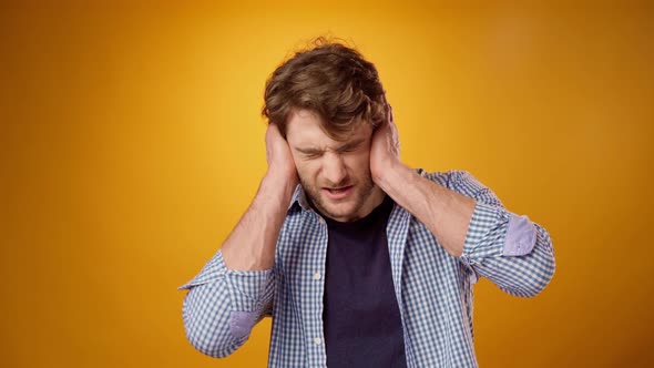 Young Man Suffering From Headache Touching Head Yellow Background