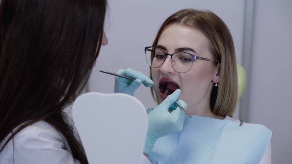 Happy Dentist Showing Her Patient at Mirror Her Healthy Smile Using Dental Tools