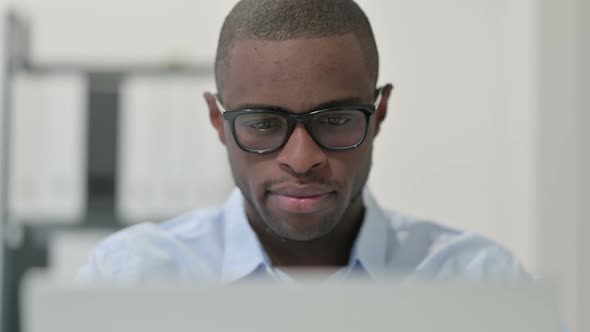 Close Up of African Man Doing Thumbs Down with Laptop