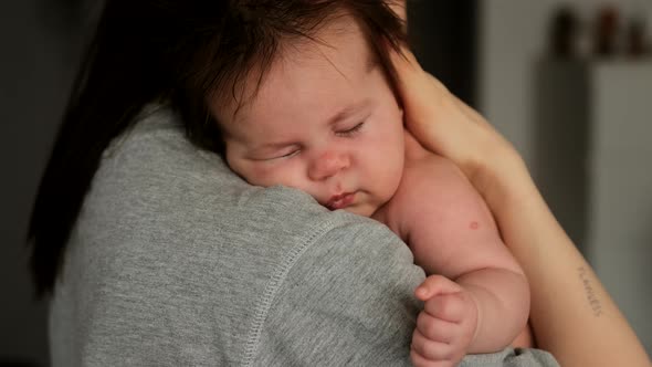 Authentic young mother holding newborn baby lulls to sleep and care for the child.