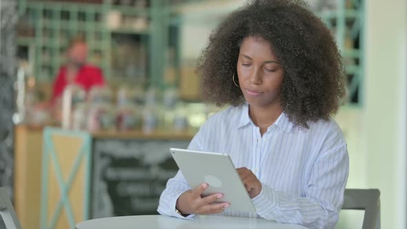 Serious Professional African Businesswoman Using Tablet in Cafe