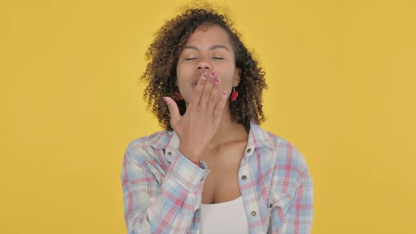 Young African Woman Giving Flying Kiss By Hands on Yellow Background