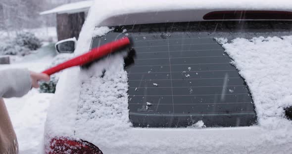 Woman Cleaning Snow From Her Car Rear Window