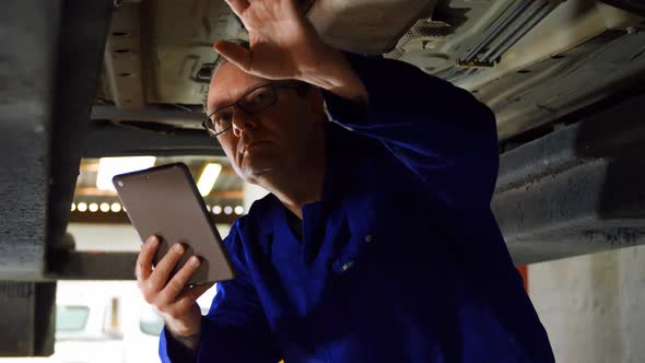 Mechanic using digital tablet while examining a car 4k