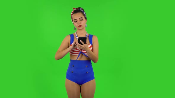 Beautiful Girl in a Swimsuit Is Angrily Texting on Her Phone. Green Screen