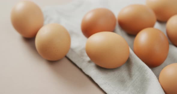 Video of close up of eggs and on rustic cloth on beige background