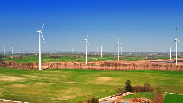 Aerial view of Farm of white wind turbines on spring field