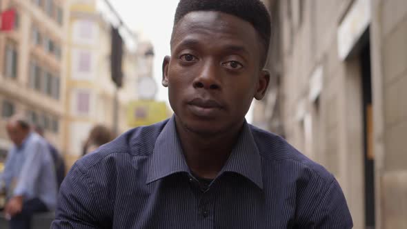 Sad depressed young black african man staring at camera in the street