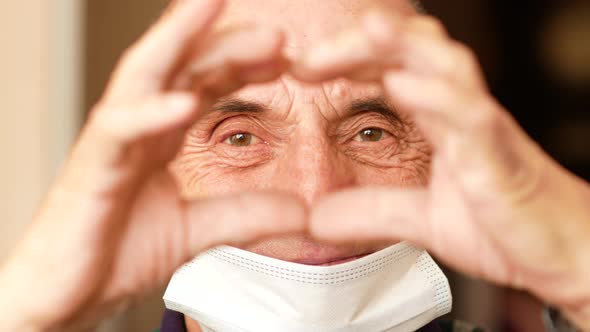 Portrait of Caucasian male 70 years old making heart shaped gesture with hands