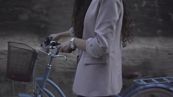 Cropped Image Of CurlyHaired Female Wearing Casual Clothes Is Walking With A Bicycle