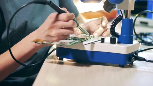 Repairman Soldering Tiny Details Through Microscope