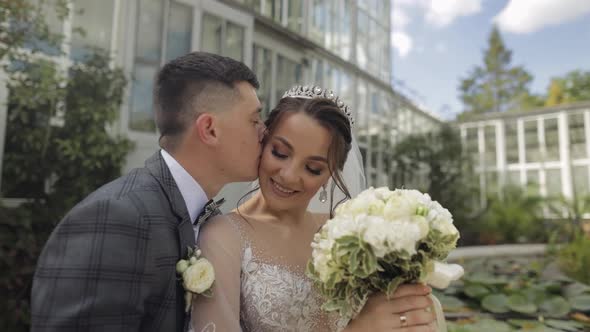 Newlyweds. Caucasian Bride and Groom Walking in Park. Embracing, Hugs. Making a Kiss. Wedding Couple