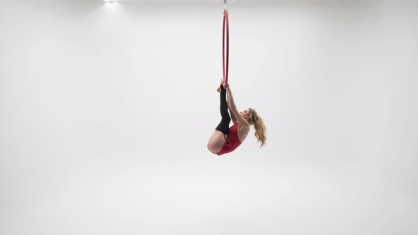 Gymnastics In A Red Dress Hanging On The Feet In The Air Ring