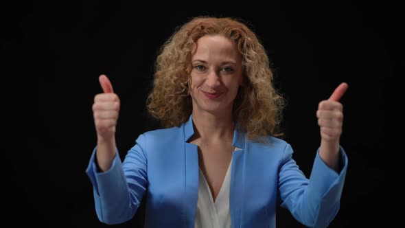Happy Woman Showing Thumbs Up Posing in Camera Flashes at Black Background