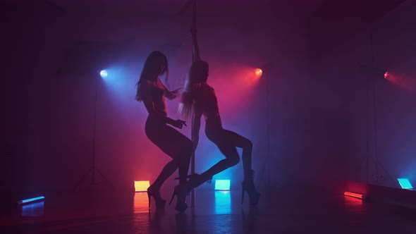 Dancers in Dark Studio with Pole at Blue and Red Smoke. Beautiful Dancing Girls