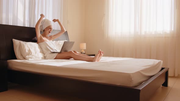 Excited Young Woman Winner Looks at Laptop Celebrates Online Success Sits on