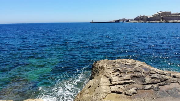 Aerial view towards a fast motor boat sailing in emerald blue sea from Sliema, Malta, Valletta