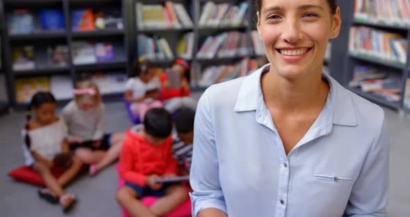 Front view of happy Caucasian female teacher standing in the school library 4k