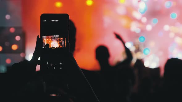 Silhouette of Woman Hands Making Video with Smartphone at Live Rock Concert. Slow Motion