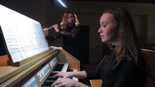 Female Flutist and Organist Playing Music By Notes in Church